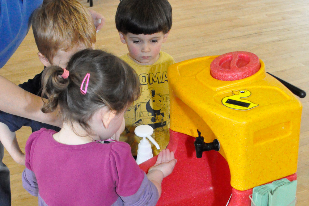 Children washing hands in nursery school with mobile sink