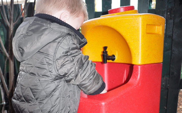 Children washing hands outdoors with portable sinks