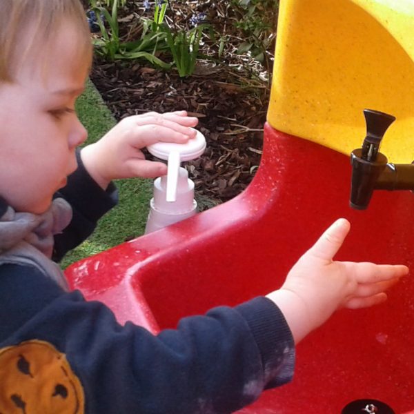 Child using a Teal soap dispenser