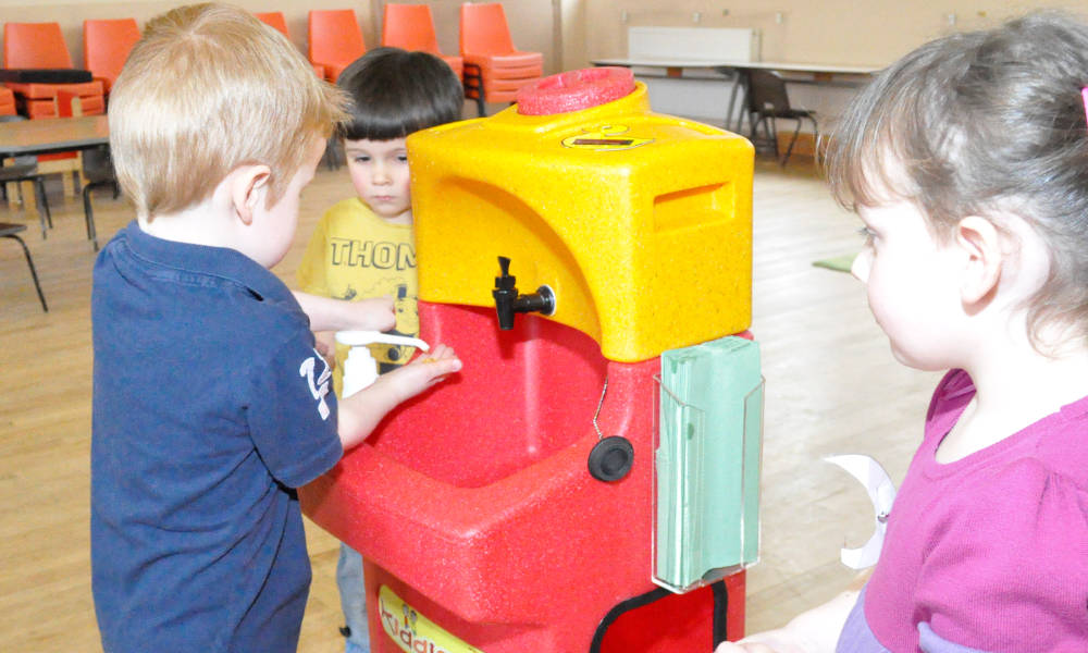 Children learning how to wash hands with a portable handwash station