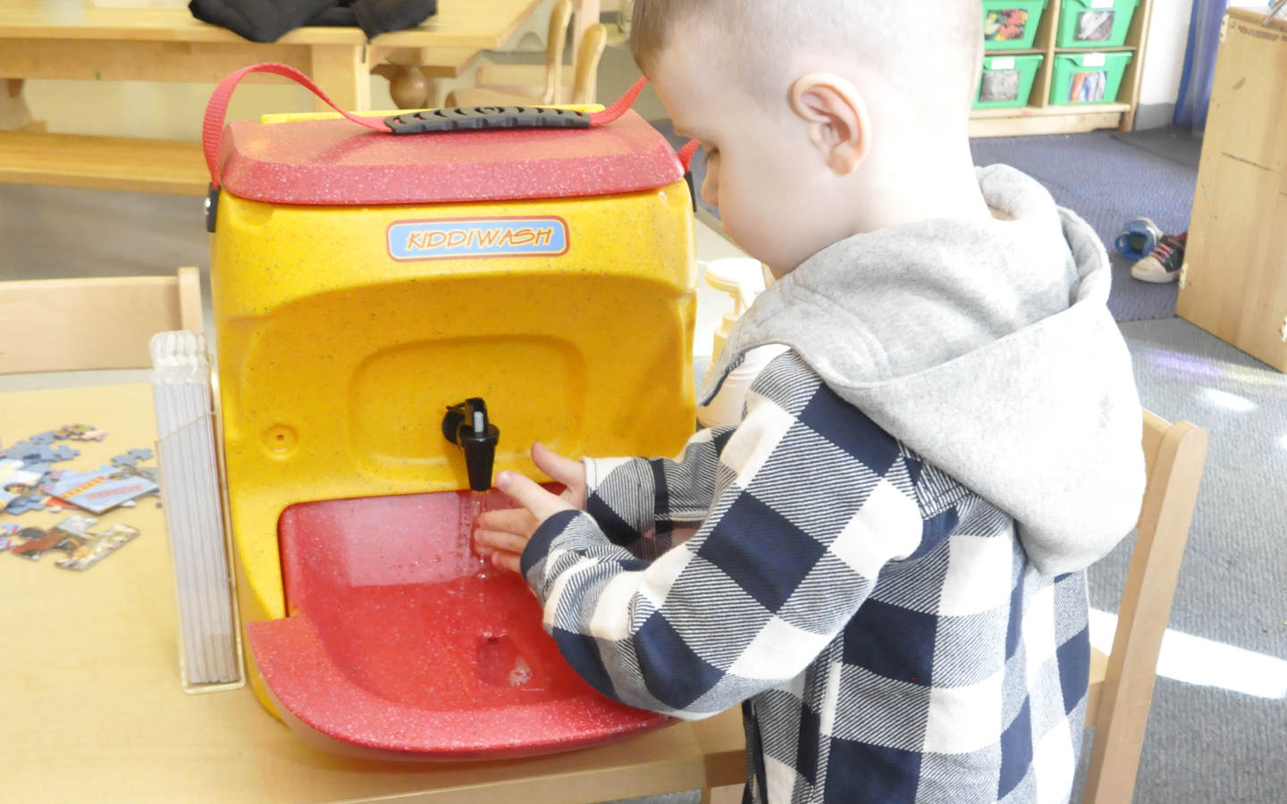 A youngster washing hands with a KiddiWash Xtra unit